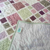 Corner detail of handmade quilt with SQ² Creations fabric label and coordinating backing.