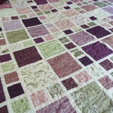 Close-up of lavender and green patchwork squares on handmade king quilt showing intricate stitching and soft cotton texture