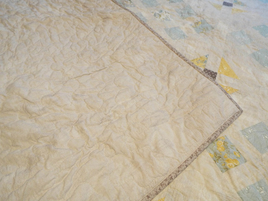 Folded corner showing fabric patterns and cotton backing of the Honeybloom queen quilt