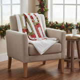 Neutral armchair with holiday quilt draped over it in the corner of an airy room