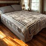 Handmade black and white quilt with rectangular blocks styled on a wooden bed in a cozy farmhouse-inspired bedroom