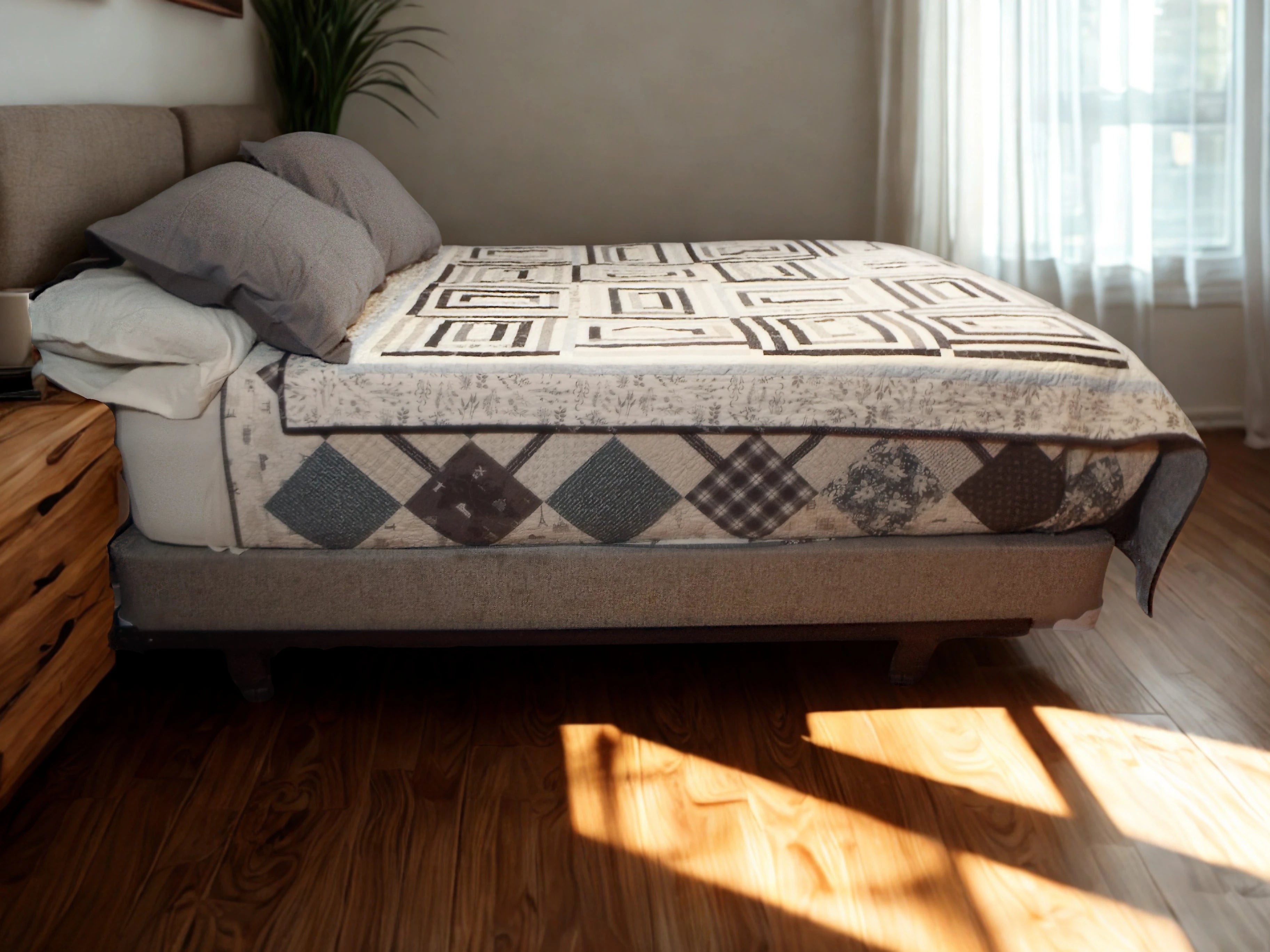 Twin-sized handmade quilt in black and white rectangle design laid flat on a modern upholstered bed in a bright minimalist room.
