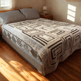 Handmade twin black and white quilt with geometric rectangles design displayed on a modern bed in a minimalist bedroom.