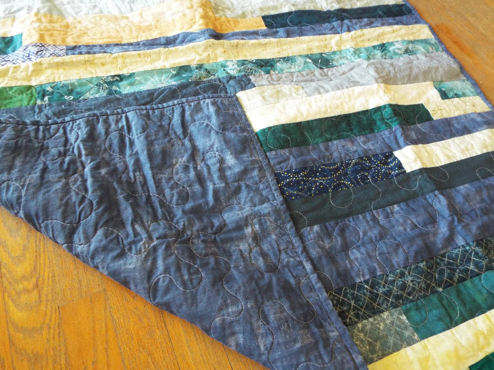Angled shot of quilt with corner flipped up so show backing