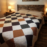 Handmade queen quilt with floral patchwork in autumn tones on a cozy wood-floor bedroom bed.