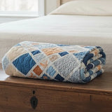 Folded Softspoken Summer king quilt resting on a wooden chest, showing its refined finish and cozy weight.