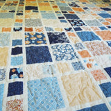 Overhead view showing the full quilt pattern and color field of blues, creams, and soft terracotta tones.