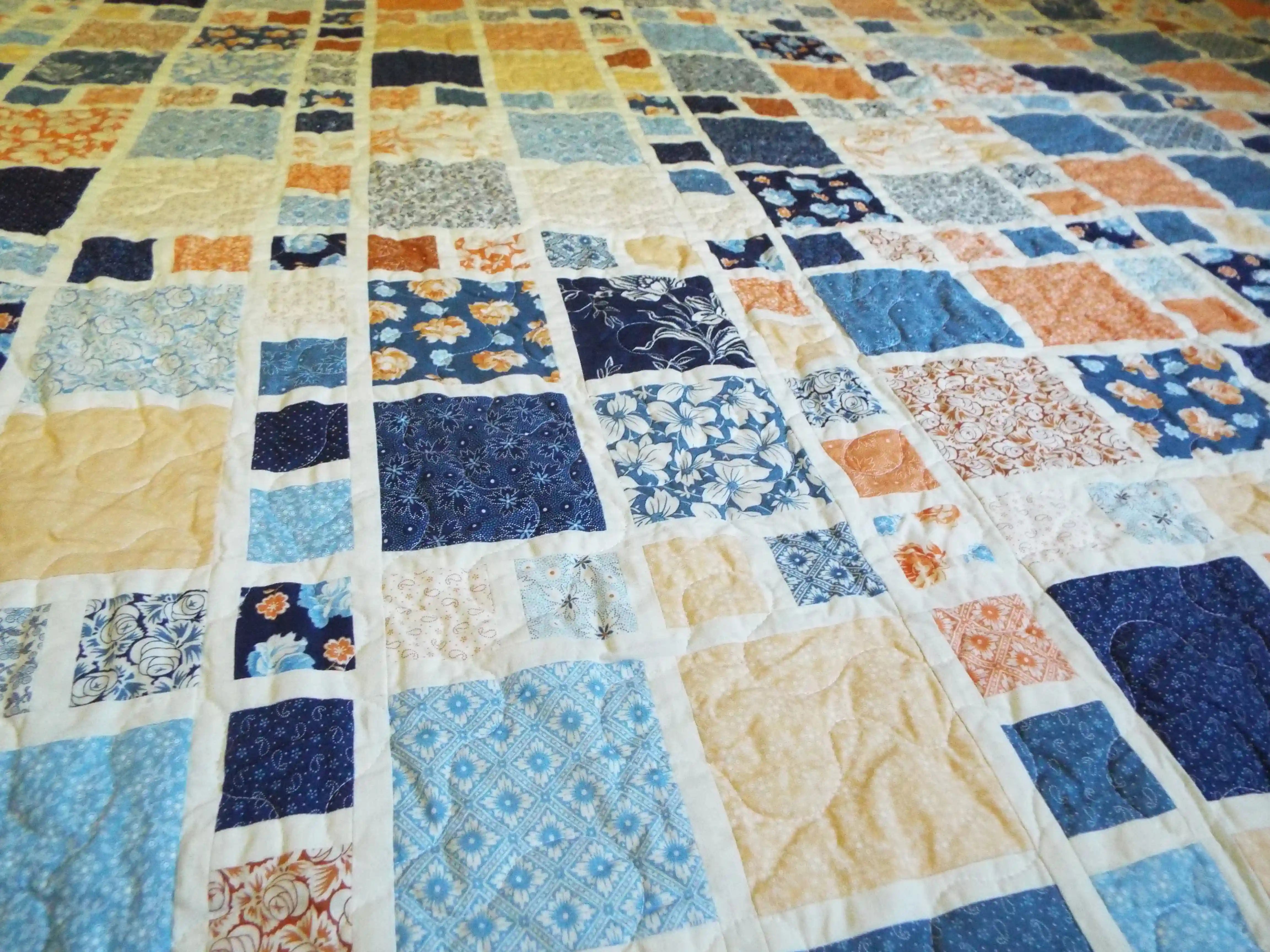 Overhead view showing the full quilt pattern and color field of blues, creams, and soft terracotta tones.