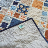 Signature SQ² Creations label and soft cotton backing showing the maker’s tag and quilt texture.
