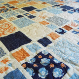 Close mid-range view showing intricate patchwork blocks and gentle quilting texture across the fabric.