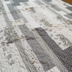 Angled flat lay of Starlit Trails gray baby quilt