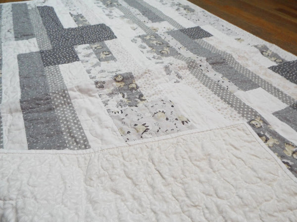 Corner flipped to show backing on Starlit Trails gray baby quilt