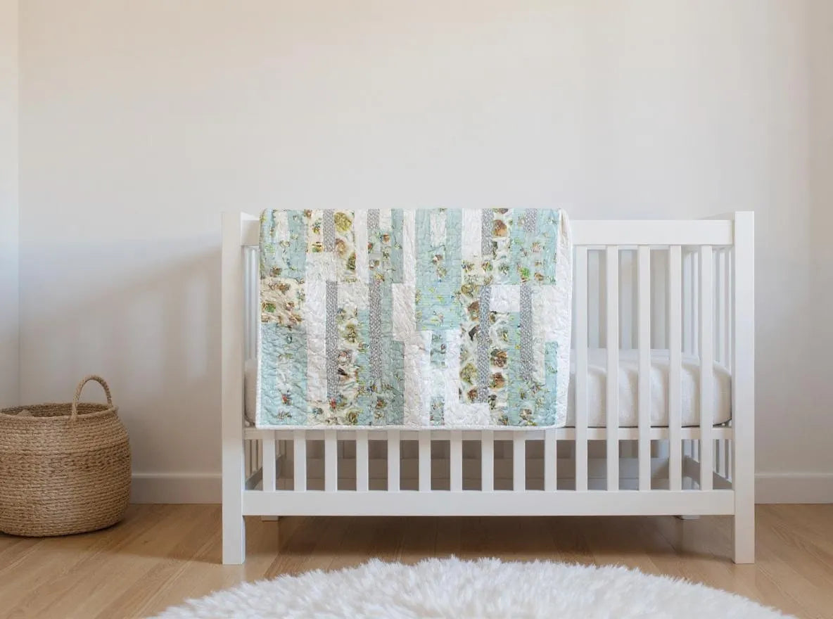 Twilight Tails blue baby quilt draped over white crib in neutral nursery
