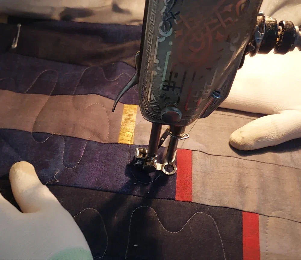 Hands guiding quilt under a Singer 201 sewing machine
