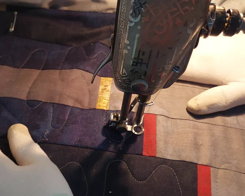 Hands guiding quilt under a Singer 201 sewing machine