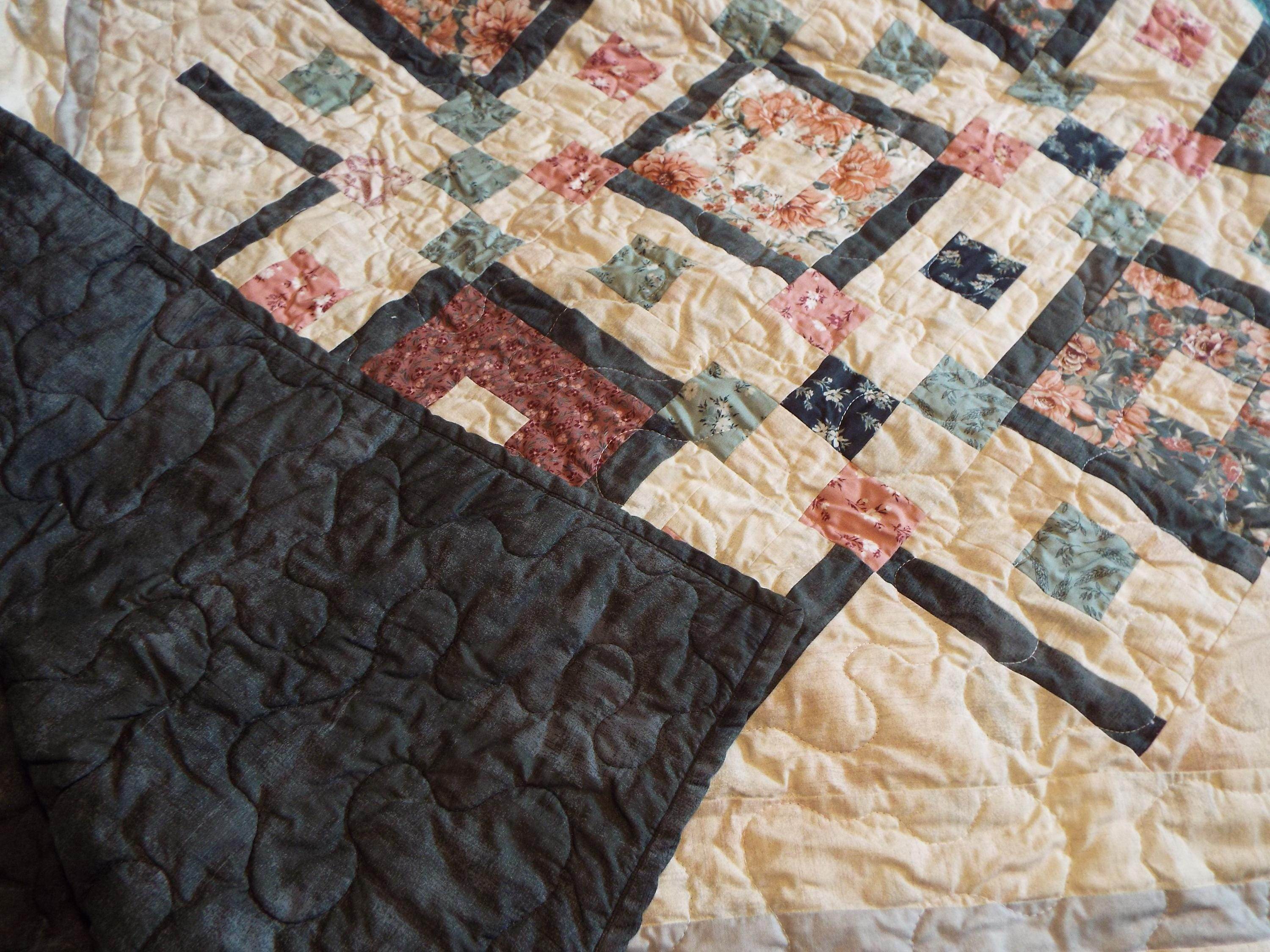Handmade twin floral quilt with corner flipped up to show backing and quilt top together