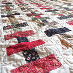 Angled shot of holiday throw in traditional colors in a brick piecing pattern