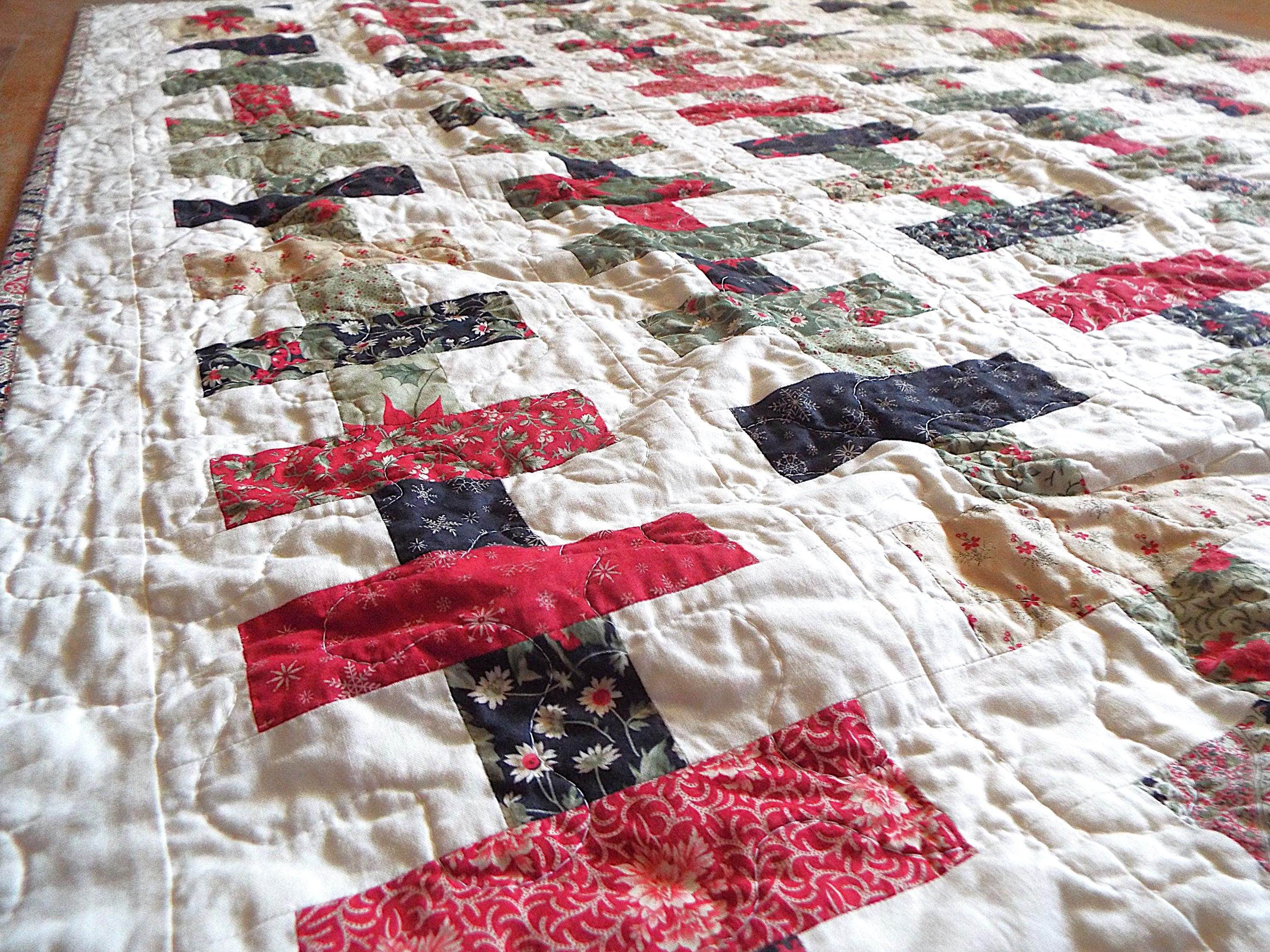 Angled shot of holiday throw in traditional colors in a brick piecing pattern