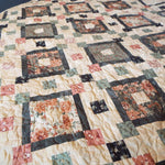 Close up of stitching on  handmade quilt done in rose, green, and cream with gray accents