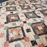 Close up of stitching on  handmade quilt done in rose, green, and cream with gray accents