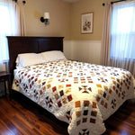 Adamstown handmade queen quilt shown on a bed with a dark wooden headboard in a minimal bedroom