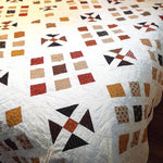 View of Adamstown handmade queen quilt draped on a queen size bed showing length of drape on side and foot of bed