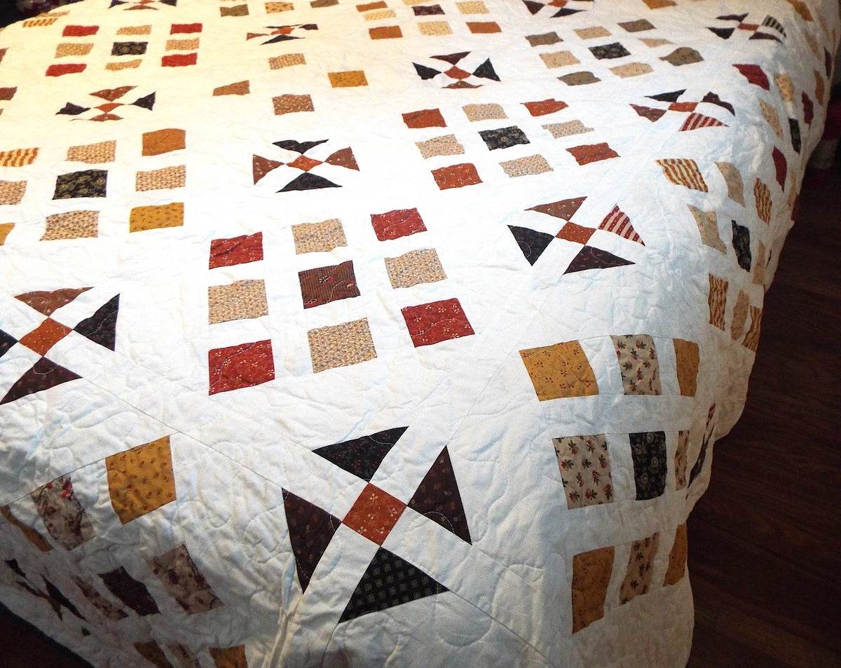 View of Adamstown handmade queen quilt draped on a queen size bed showing length of drape on side and foot of bed