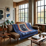 Air Force Airman Throw Quilt is draped over a brown leather sofa in a modern, sunlit living room with wood walls, windows, and bookshelves.
