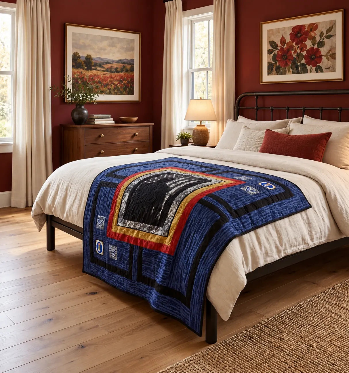 A styled bedroom scene showing a bed dressed in a cream bedding set with Air Force Airman Throw Quilt. The room has dark red walls, wood floors, a wooden dresser, and framed floral paintings.