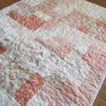 Angled lay of quilt showing detail in fabrics and stitching
