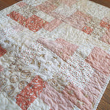 Angled lay of quilt showing detail in fabrics and stitching