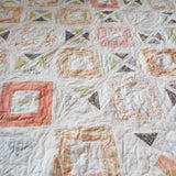 Angled lay of handmade lap quilt showing texture and quilt stitching.
