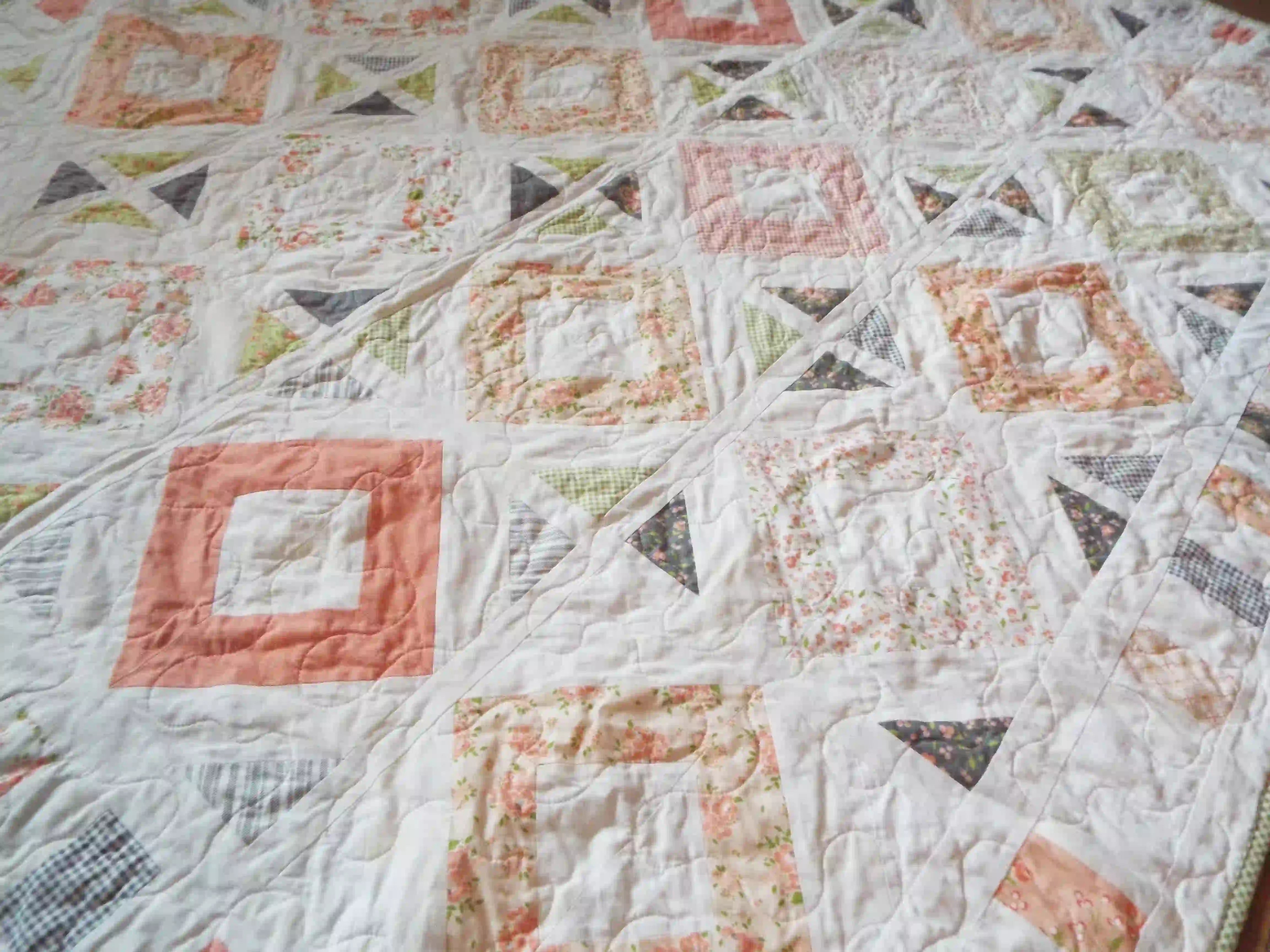 Angled lay of handmade lap quilt showing texture and quilt stitching.