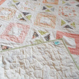 Handmade quilt showing corner flipped up to see backing, binding, and quilt top.