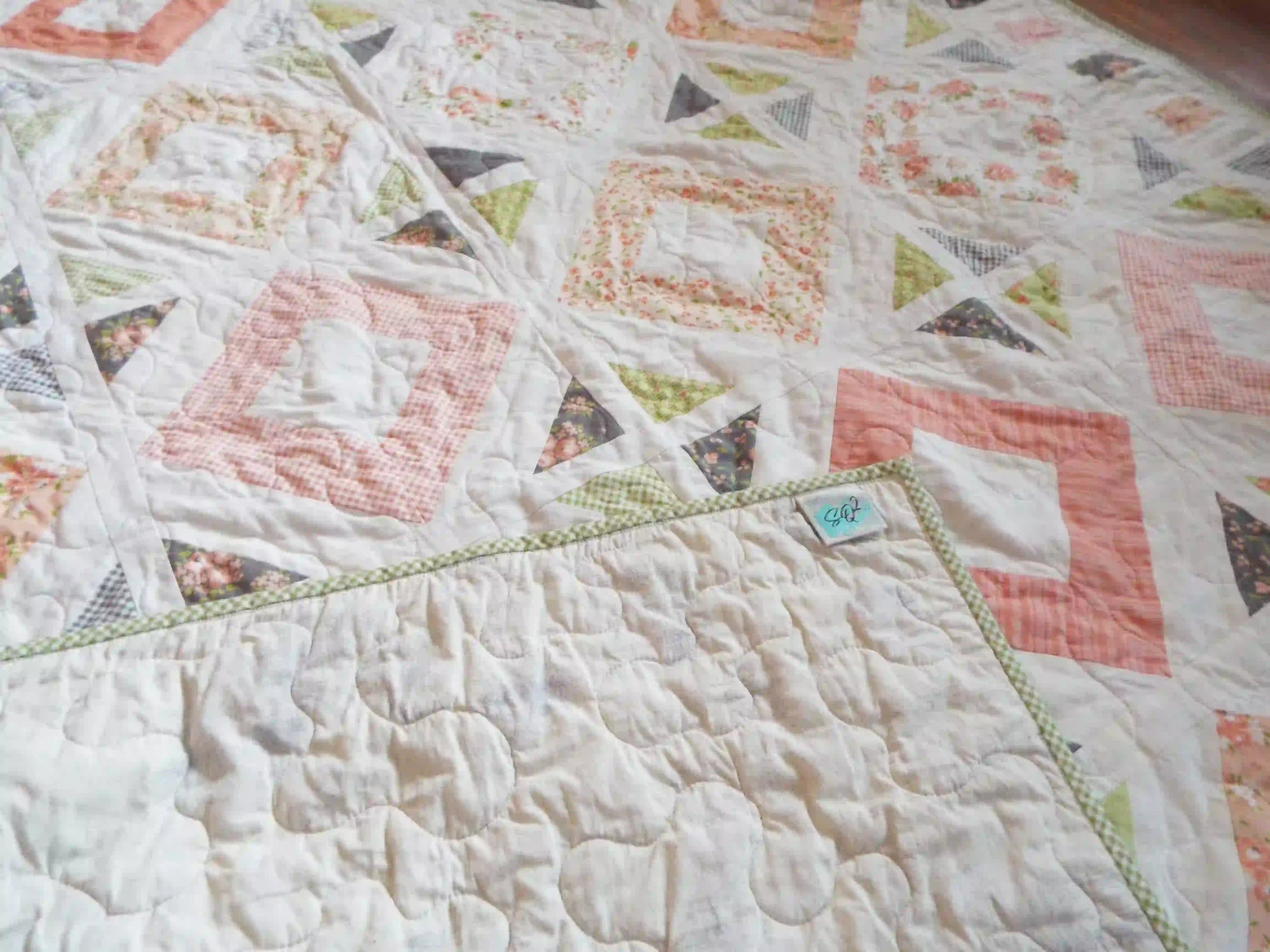 Handmade quilt showing corner flipped up to see backing, binding, and quilt top.