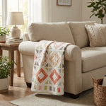 Handmade lap quilt shown folded over the arm of a sofa.