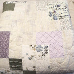 Twin sized quilt in purples and greens folded on a bed