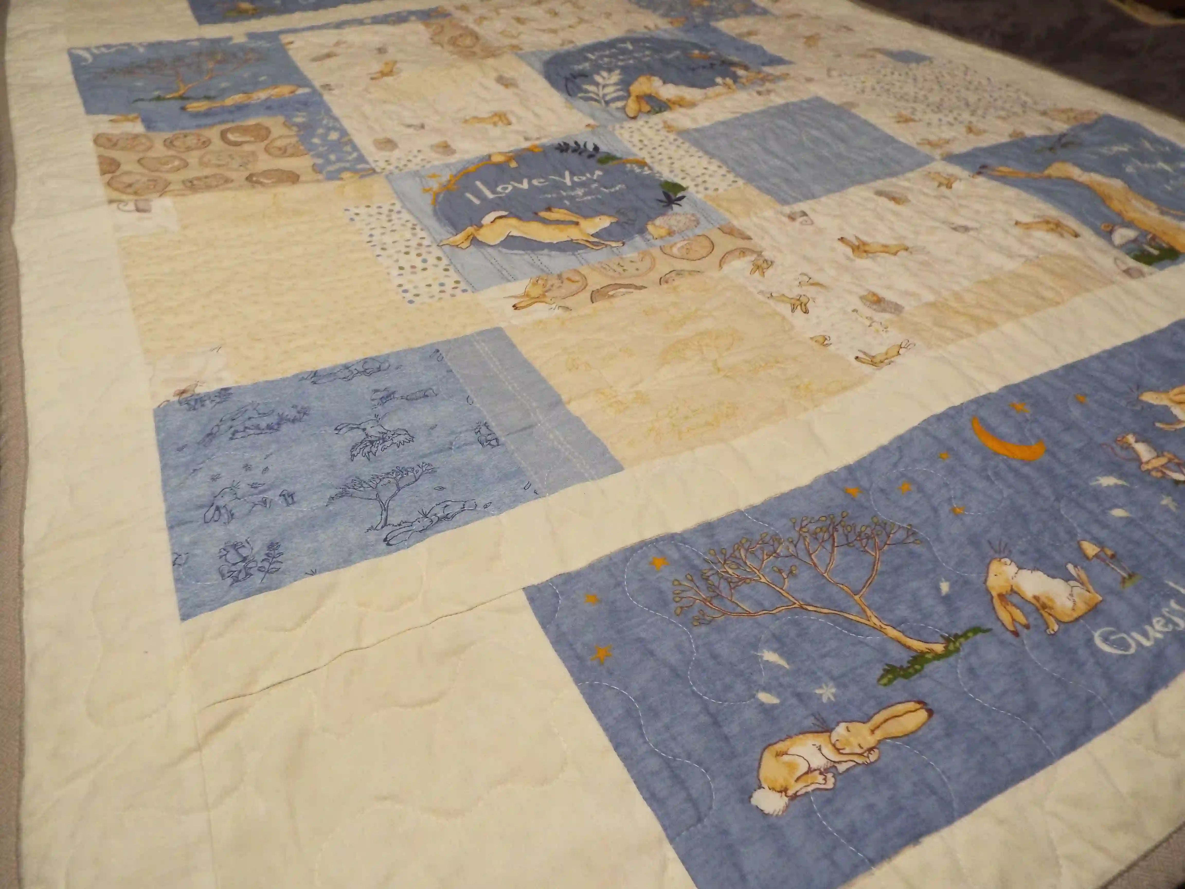 Overhead view of a blue bunny baby quilt with airy piecing and calming neutral tones, styled flat for a full view of the pattern and fabric details