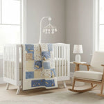 Heirloom-quality baby quilt in pale blues and creams draped on a white crib in a minimalist nursery with gray walls and modern mobile; a quiet, handmade accent in a gender-neutral setting.