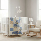 Heirloom-quality baby quilt in pale blues and creams draped on a white crib in a minimalist nursery with gray walls and modern mobile; a quiet, handmade accent in a gender-neutral setting.
