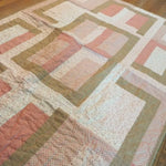 Angled lay of Blushing Pathways Baby Quilt showing closer look of fabric.