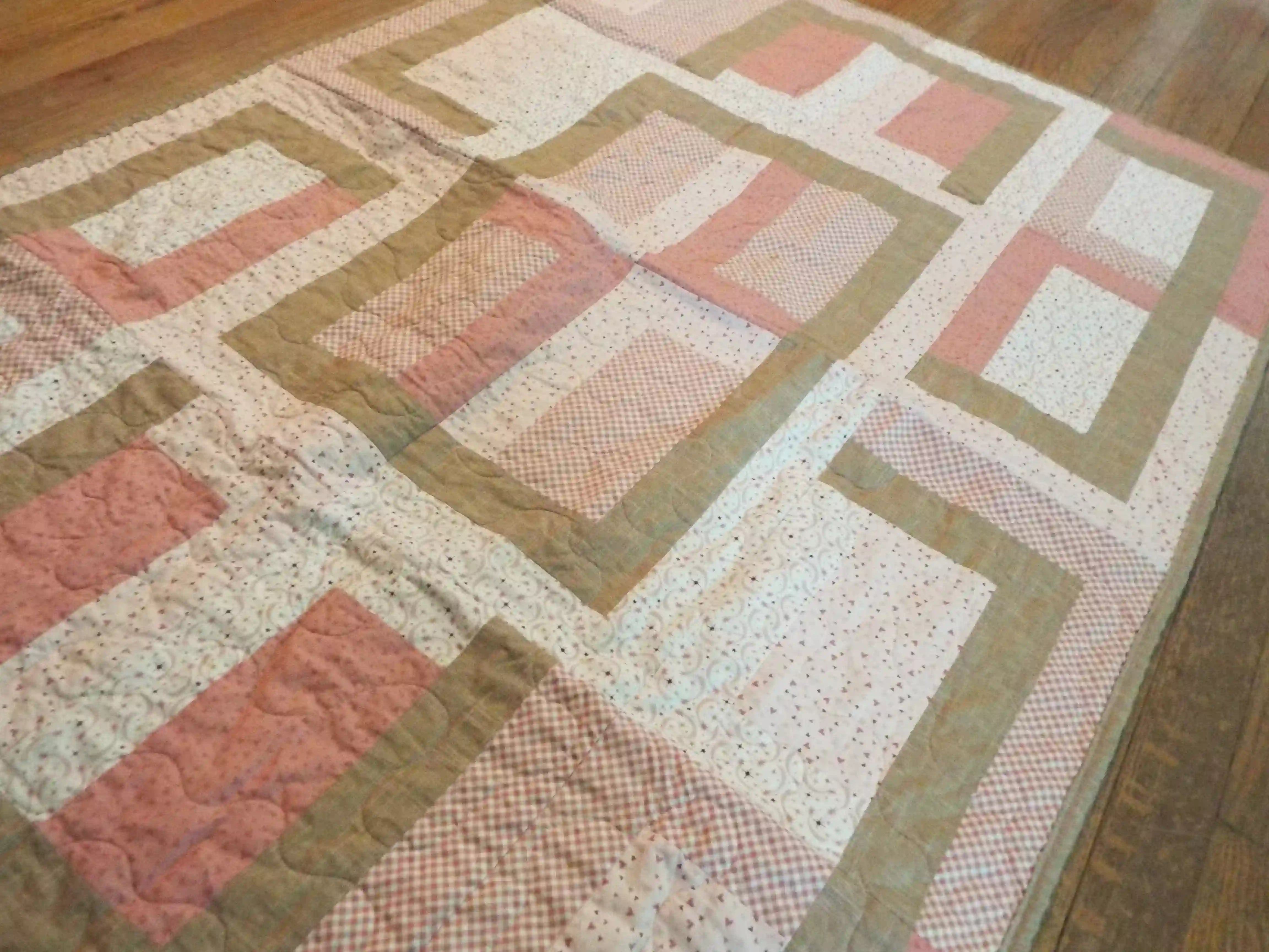 Angled lay of Blushing Pathways Baby Quilt showing closer look of fabric.