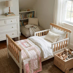 Blushing Pathways Baby Quilt shown folded at the foot of a child's bed.