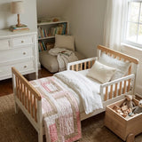 Blushing Pathways Baby Quilt shown folded at the foot of a child's bed.