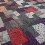 Angled lay of Bramble & Stone King quilt showing stitching and fabrics used in construction.