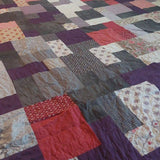 Angled lay of Bramble & Stone King quilt showing stitching and fabrics used in construction.