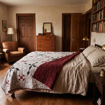 A cozy bedroom scene featuring a bed dressed with Cartographer's Notes Queen Quilt, surrounded by warm wood furniture, bookshelves, and a leather armchair.