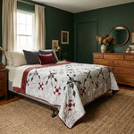 A styled bedroom interior featuring a bed with Cartographer's Notes Queen Quilt, set against dark green walls with a wooden dresser, nightstand, and natural jute rug.