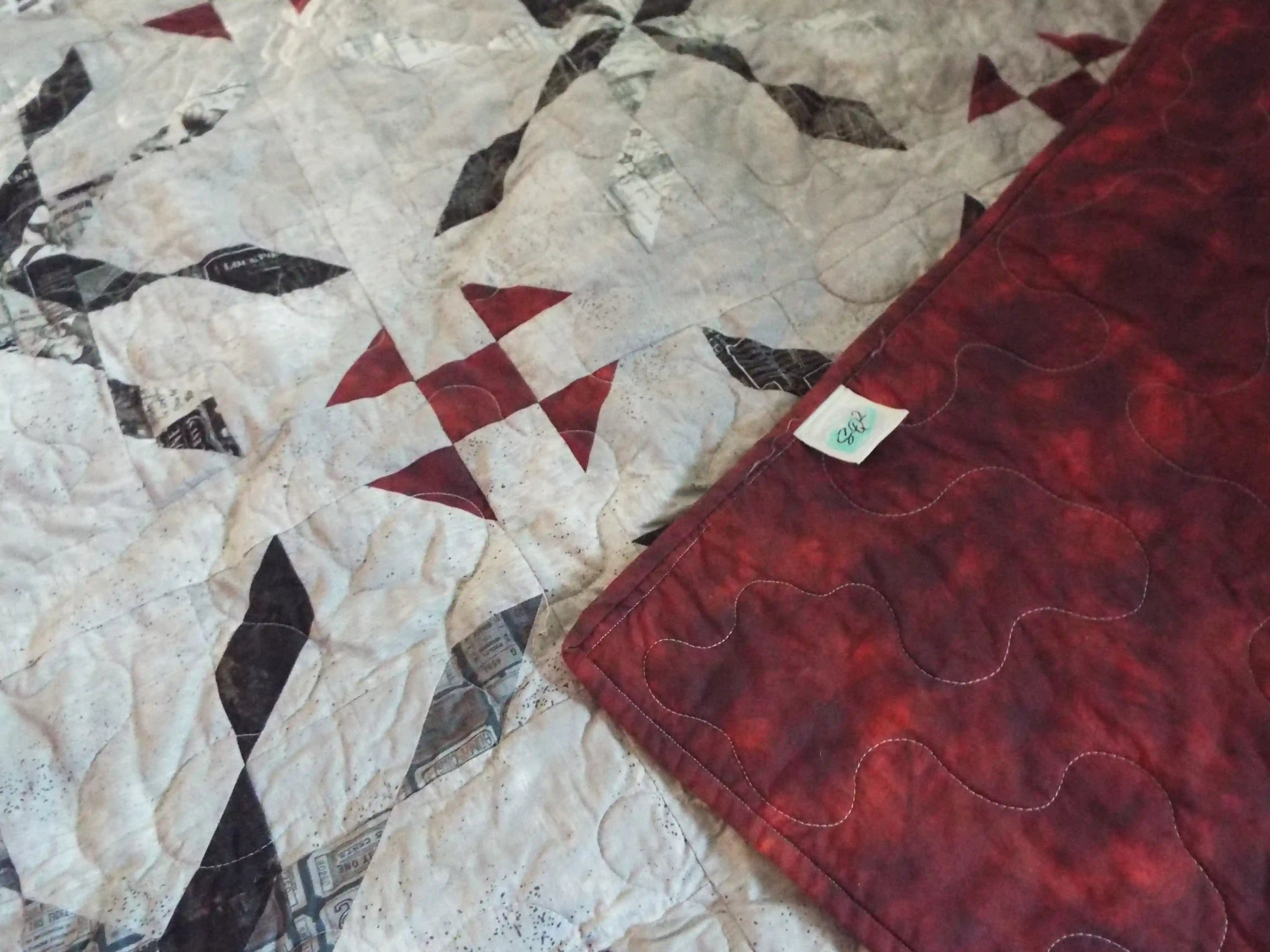 Cartographer's Notes Queen Quilt shown with corner flipped over to see backing and stitching detail.