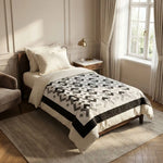 Black and white quilt shown on a twin bed in a traditionally styled room with architectural molding 